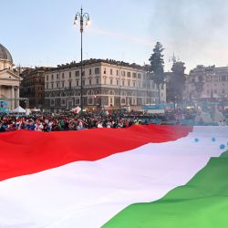 Una bandera gigante de Italia es mostrada por los aficionados italianos mientras ven en una pantalla gigante la transmisión del partido de fútbol de cuartos de final de la UEFA EURO 2020 entre Bélgica e Italia desde la zona oficial de aficionados en la Piazza del Popolo en Roma. | Foto:Andreas Solaro / AFP