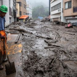 Un trabajador de rescate remueve el lodo y los escombros en la escena de un deslizamiento de tierra después de días de fuertes lluvias en Atami en la prefectura de Shizuoka. | Foto:Charly Triballeau / AFP