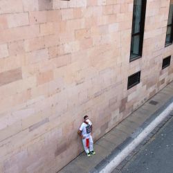 Un participante se apoya en un muro mientras participa en la celebración simbólica del primer encierro de las fiestas de San Fermín, cancelado por segundo año consecutivo como parte de las medidas preventivas para luchar contra la propagación del COVID-19, en Pamplona, norte de España. | Foto:Ander Gillenea / AFP