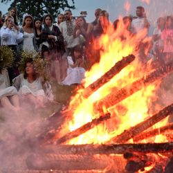 La gente asiste a una hoguera durante las celebraciones de la noche de Kupala en Pyrohiv, cerca de Kiev. - Durante la celebración, un antiguo ritual eslavo relacionado con el solsticio de verano, la gente lleva coronas, salta sobre las hogueras y se baña desnuda en ríos y lagos. | Foto:Sergei Supinsky / AFP