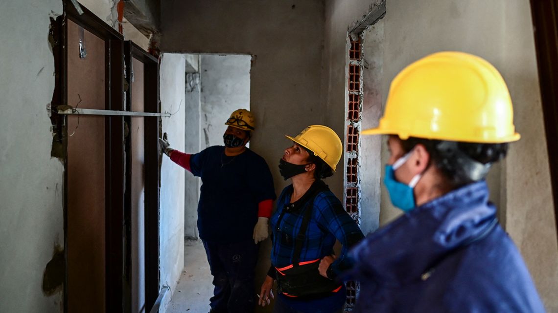 Female bricklayers work in the construction of houses in Avellaneda, Buenos Aires province, Argentina, on June 22, 2021. With a tight sash, a woman bricklayer pulls the rope without a pulley to lift buckets full of sand to a rooftop. A group of women build walls and chop stone in Argentina: they not only build houses, they also deconstruct machismo in masonry.