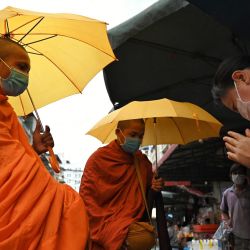 Una mujer hace un gesto de oración mientras ofrece limosna a los monjes budistas en un mercado de Phnom Penh. | Foto:Tang Chhin Sothy / AFP