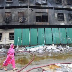 Un trabajador de la confección pasa por delante de la fábrica quemada después de que se apagara un incendio en Rupganj. | Foto:Munir Uz zaman / AFP