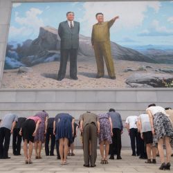 La gente se inclina ante un mosaico de retratos de los difuntos líderes norcoreanos Kim Il Sung y Kim Jong Il, en el cruce de Dongmun, en el distrito de Daedonggang de Pyongyang, con motivo del 27º aniversario de la muerte de Kim Il Sung. | Foto:Kim Won Jin / AFP