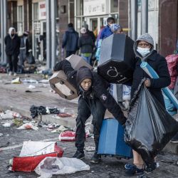 Unos saqueadores se llevan los pocos objetos que quedan por recoger en un centro comercial vandalizado en Vosloorus. | Foto:Marco Longari / AFP