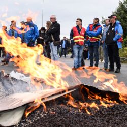 Empleados de EDF (Electricite De France) de pie frente a la quema de pallets durante una concentración en la entrada de la central eléctrica de carbón de EDF de Cordemais, al oeste de Francia, para protestar contra el abandono del proyecto Ecocombust que consiste en sustituir el carbón por pellets de biomasa densificada. | Foto:Sebastien Salom-Gomis / AFP