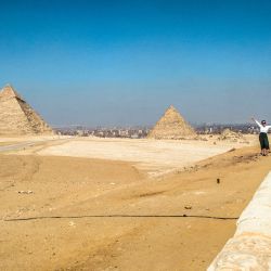 Un turista posa para la cámara en un promontorio con vistas a la Gran Pirámide de Keops, la Pirámide de Kefrén y la Pirámide de Menkheres en la antigua necrópolis de Giza en las afueras del oeste de la ciudad gemela de la capital egipcia. | Foto:Khaled Desouki / AFP