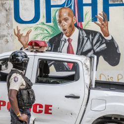 Un agente de policía permanece junto a una pared pintada con un mural del difunto presidente haitiano Jovenel Moise después de que agentes del FBI y equipos forenses realizaran registros en su residencia en Puerto Príncipe, tras su asesinato. | Foto:Valerie Baeriswyl / AFP
