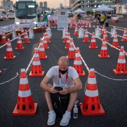 Un hombre mira su teléfono móvil en el centro de autobuses del centro de medios olímpicos en Tokio, antes de los Juegos Olímpicos de Tokio 2020. | Foto:Loic Venance / AFP