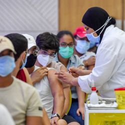 Un joven tunecino recibe una dosis de la vacuna china Sinopharm en el Palacio de Congresos de la capital, Túnez. | Foto:Fethi Belaid / AFP