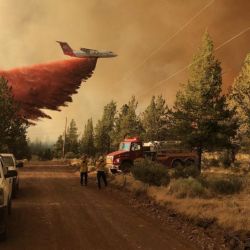 Esta foto proporcionada por el Departamento Forestal de Oregón muestra un avión cisterna de extinción de incendios lanzando un retardante sobre el incendio de Grandview, cerca de Sisters, Oregón. | Foto:Handout / Departamento Forestal de Oregón / AFP