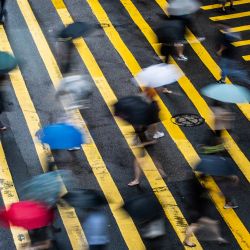 Peatones con paraguas cruzan una carretera en Hong Kong, mientras los patrones climáticos del tifón Cempaka traen fuertes lluvias a la ciudad. | Foto:Isaac Lawrence / AFP