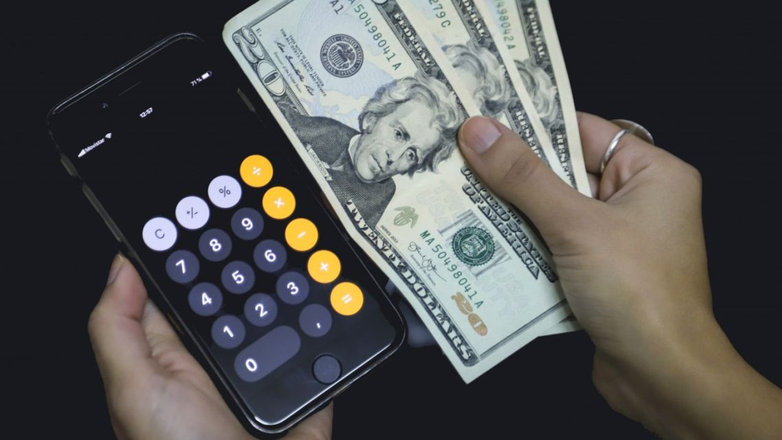 A calculator app on a phone and greenbacks.
