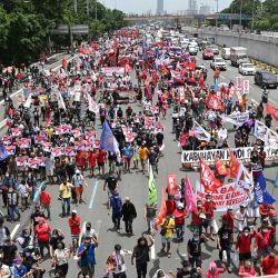 Manifestantes marchan por una autopista en su camino hacia el Congreso para coincidir con el discurso anual del presidente sobre el estado de la nación que se espera más tarde en el día, en los suburbios de Manila. | Foto:Ted Aljibe / AFP