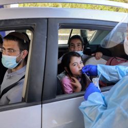 Un médico realiza una prueba de hisopo de coronavirus COVID-19 en un niño en un vehículo en un complejo de pruebas de coronavirus del comando Home Front en Jerusalén. | Foto:Menahem Kahana / AFP