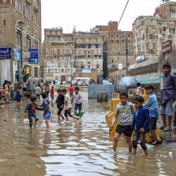 Unos niños caminan por una calle inundada tras las fuertes lluvias en el casco antiguo de la capital de Yemen. | Foto:Mohammed Huwais / AFP