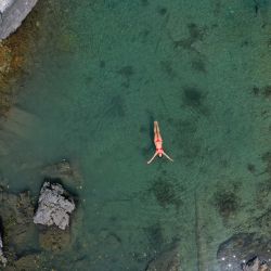 Una mujer nada para refrescarse en el lago de Xhema, un pequeño lago natural situado en el Parque Nacional de Valbona, cerca de Dragobi. - Una ola de calor azota Albania, donde las temperaturas alcanzan un máximo de 43. | Foto:Gent Shkullaku / AFP