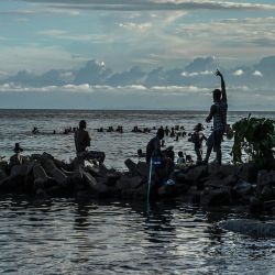 Migrantes varados de Haití disfrutan de la tarde en la playa mientras esperan un barco que los lleve a Capurgana, cerca de la frontera con Panamá, en Necoclí, Colombia. | Foto:Joaquin Sarmiento / AFP