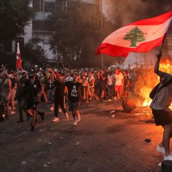 Un manifestante con una bandera nacional libanesa durante los enfrentamientos con el ejército y las fuerzas de seguridad cerca de la sede del parlamento libanés en el centro de la capital, Beirut, en el primer aniversario de la explosión que asoló el puerto y la ciudad. | Foto:Patrick Baz / AFP