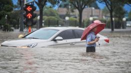 un hombre vadeando un coche sumergido a lo largo de una calle inundada tras las fuertes lluvias en Zhengzhou, en la provincia central china de Henan.
