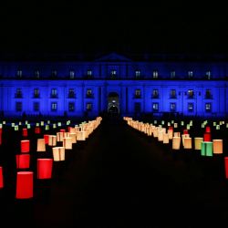 Vista del palacio presidencial de La Moneda iluminado durante un homenaje a las víctimas de la pandemia del coronavirus COVID-19, en Santiago. | Foto:Claudio Reyes / AFP