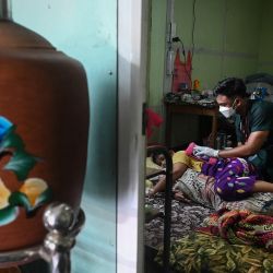 Esta foto muestra a un voluntario tratando a un paciente con el coronavirus Covid-19 en su casa en el distrito de Taungoo, en la región de Bago de Myanmar, a unos 220 km de Yangon. | Foto:Ye Aung Thu / AFP