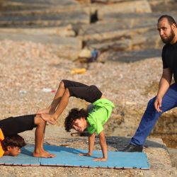 El entrenador palestino Bashar Musa supervisa las poses de los jóvenes contorsionistas que pretende inscribir en competiciones internacionales, durante una sesión de entrenamiento en la playa de la ciudad de Gaza, en la franja palestina. | Foto:Mohammed Abed / AFP
