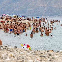 La gente disfruta del mar en la playa de Torre Faro durante un caluroso día de verano en Mesina. | Foto:Giovanni Isolino / AFP