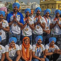 Los jugadores del equipo de hockey de la India (con turbante / tocado azul) presentan sus respetos en el templo dorado de Amritsar a su regreso a casa tras ganar la medalla de bronce en los Juegos Olímpicos de Tokio. | Foto:Narinder Nanu / AFP