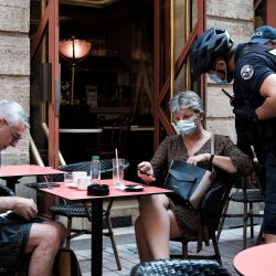 Un policía comprueba la tarjeta sanitaria de un cliente en un bar de Burdeos, suroeste de Francia. - La gente en Francia debe ahora mostrar un pase de salud para pedir un café en un café o viajar en trenes interurbanos, ya que el controvertido plan del presidente francés para apretar las infecciones y fomentar la vacunación entró en pleno vigor. | Foto:Philippe Lopez / AFP