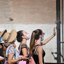 Un grupo de mujeres se refresca frente a un ventilador durante la ola de calor mientras hacen cola a la entrada del Coliseo en Roma. | Foto:Alberto Pizzoli / AFP