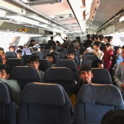 Los pasajeros afganos se sientan en el interior de un avión mientras esperan salir del aeropuerto de Kabul, después de un final sorprendentemente rápido de la guerra de 20 años de Afganistán, ya que miles de personas se agolparon en el aeropuerto de la ciudad tratando de huir de la temida línea dura de gobierno islamista del grupo. | Foto:Wakil Kohsar / AFP