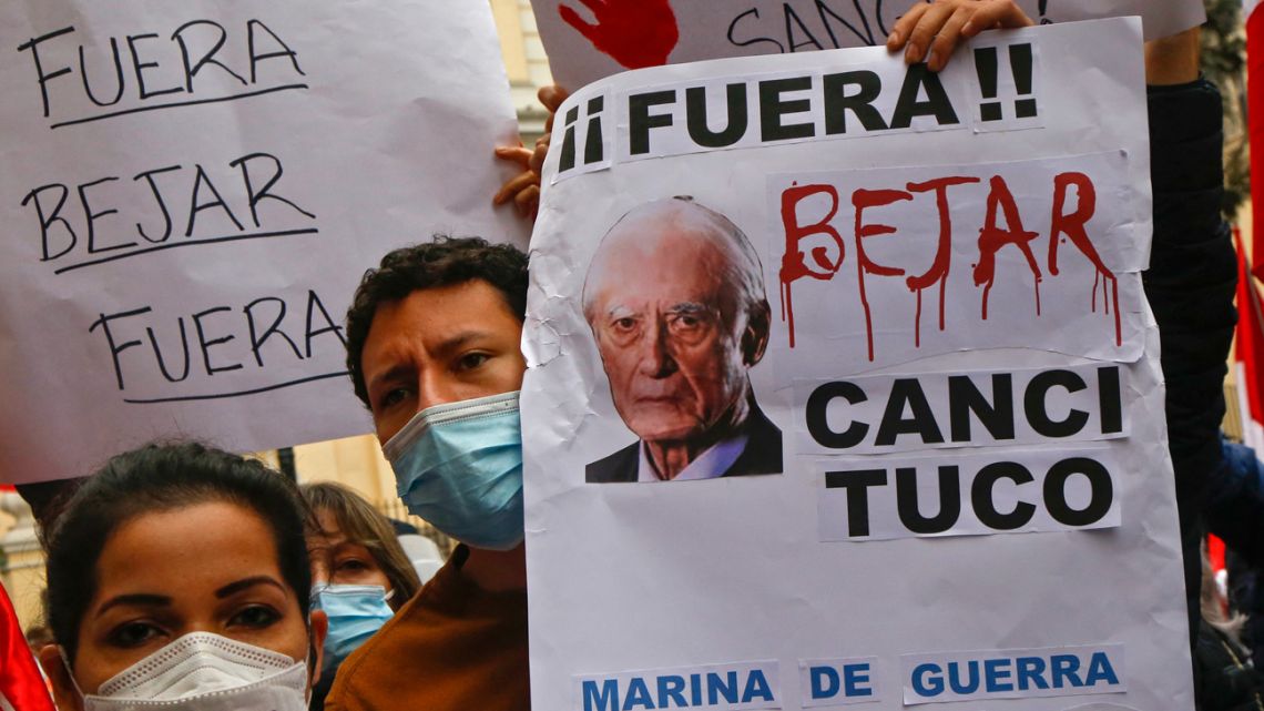 People hold signs reading “Béjar Out”, referring to Peruvian Foreign Minister Héctor Béjar during a protest outside the Foreign Affairs Ministry headquarters in Lima on August 17, 2021. 