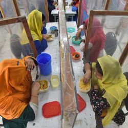 Los trabajadores comen en el comedor de la fábrica separados por tabiques como medida preventiva contra el coronavirus Covid-19 en la fábrica de ropa Civil Engineers Limited en Dhaka. | Foto:Munir Uz Zaman / AFP