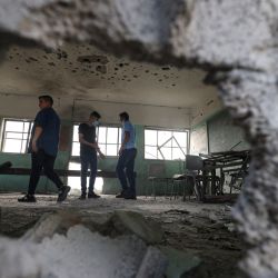 Estudiantes palestinos inspeccionan un aula de una escuela destruida durante la reciente guerra entre Israel y el movimiento palestino Hamás, en el primer día del nuevo curso académico en la ciudad de Gaza. | Foto:Mahmud Hams / AFP