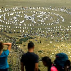 La gente observa desde arriba una danza ritual de los miembros del movimiento religioso internacional llamado la Hermandad Blanca en la cima de la montaña de Rila, cerca del lago Babreka. | Foto:Nikolay Doychinov / AFP
