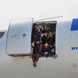 Los afganos suben a un avión y se sientan junto a la puerta mientras esperan en el aeropuerto de Kabul, tras el sorprendente y rápido final de la guerra de 20 años en Afganistán, cuando miles de personas se agolparon en el aeropuerto de la ciudad tratando de huir del temido régimen islamista de línea dura del grupo. | Foto:Wakil Kohsar / AFP