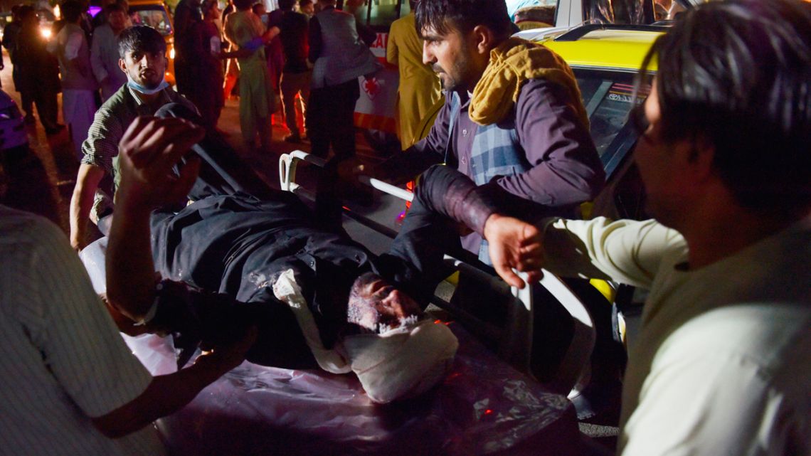 Medical and hospital staff bring an injured man on a stretcher for treatment after two blasts, which killed at least five and wounded a dozen, outside the airport in Kabul on August 26, 2021. 