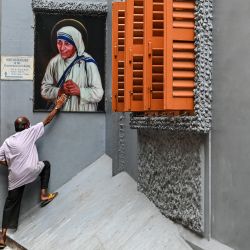 Una devota toca una imagen de la Madre Teresa en busca de bendiciones con motivo de su 111º aniversario de nacimiento, en la Casa de la Madre en Calcuta. | Foto:Dibyangshu Sarkar / AFP