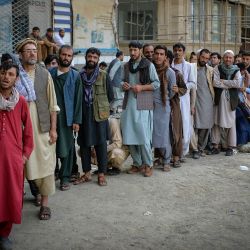 Afganos hacen cola mientras esperan que los bancos abran y operen en una zona comercial de Kabul. | Foto:Hoshang Hashimi / AFP