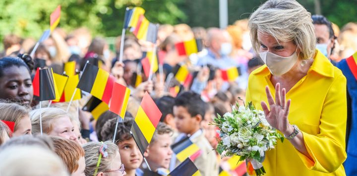 La reina Matilde de Bélgica saluda a los alumnos que sostienen banderas de Bélgica mientras participa en una visita real en la escuela primaria KAZ para el inicio del año escolar, en Zottegem, cerca de Gent.