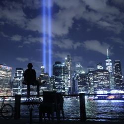 Una persona observa cómo el Tributo en Luz brilla en el cielo desde el Bajo Manhattan durante una prueba en la ciudad de Nueva York. En honor a las víctimas del atentado del 11 de septiembre de 2001 en el que murieron casi 3.000 personas en el World Trade Center, el Tribute in Light es una instalación de arte público conmemorativa que se presentó por primera vez seis meses después del 11-S y luego cada año desde entonces en el aniversario. La ciudad de Nueva York se prepara para conmemorar el 20º aniversario de los atentados terroristas del 11 de septiembre. | Foto:Chip Somodevilla / Getty Images / AFP