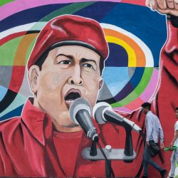 Dos hombres pasan junto a un mural que representa al fallecido presidente venezolano Hugo Chávez pintado por la brigada muralista  | Foto:Yuri Cortez / AFP