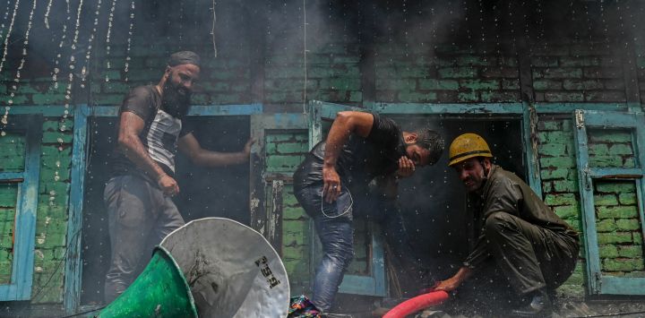 Los bomberos junto con los residentes locales trabajan para sofocar un incendio en una casa en Srinagar.