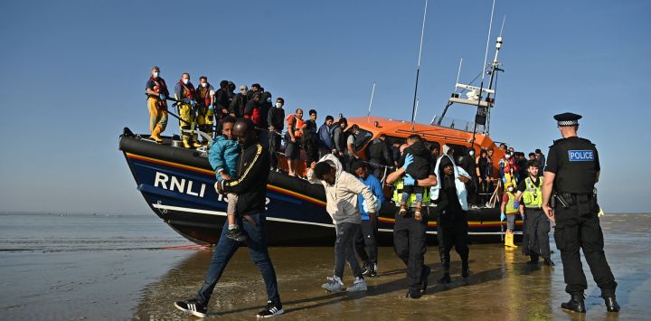 Los migrantes llevan a los niños mientras son escoltados para ser procesados después de ser recogidos por un bote salvavidas del RNLI (Royal National Lifeboat Institution) mientras cruzan el canal inglés en una playa de Dungeness, al sureste de Inglaterra.