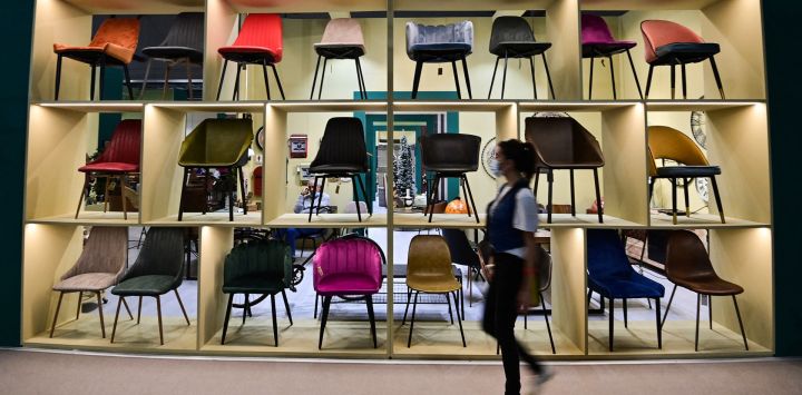 Un visitante pasa junto a las sillas expuestas en el stand de Novita Home, en el 