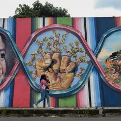 Una mujer con un bebé en brazos camina frente a un mural, en Tlaxcala, México. | Foto:Xinhua / Jesús Alvarado
