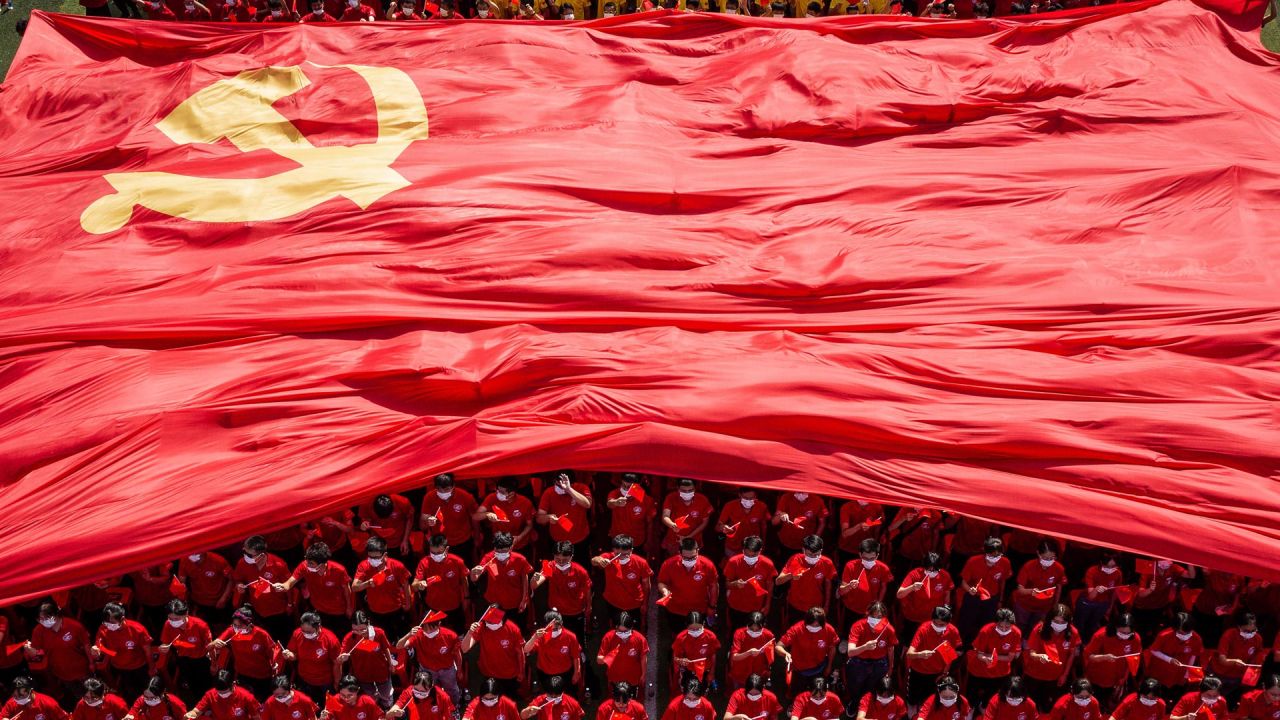 Estudiantes universitarios muestran una bandera del Partido Comunista de China para conmemorar el centenario del partido durante una ceremonia de apertura del nuevo semestre en Wuhan, en la provincia central china de Hubei. | Foto:STR / AFP