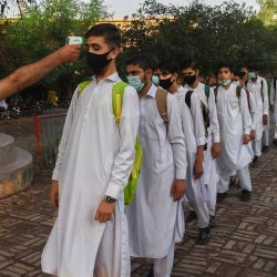 Un profesor comprueba la temperatura corporal de un estudiante mientras otros hacen cola a su llegada a una escuela en Peshawar, después de que el gobierno reabriera los institutos educativos que estaban cerrados como medida preventiva para frenar la propagación del coronavirus Covid-19. | Foto:Abdul Majeed / AFP