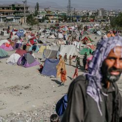 Un hombre pasa por delante de un campamento de desplazados internos en Kabul. | Foto:Bulent Kilic / AFP